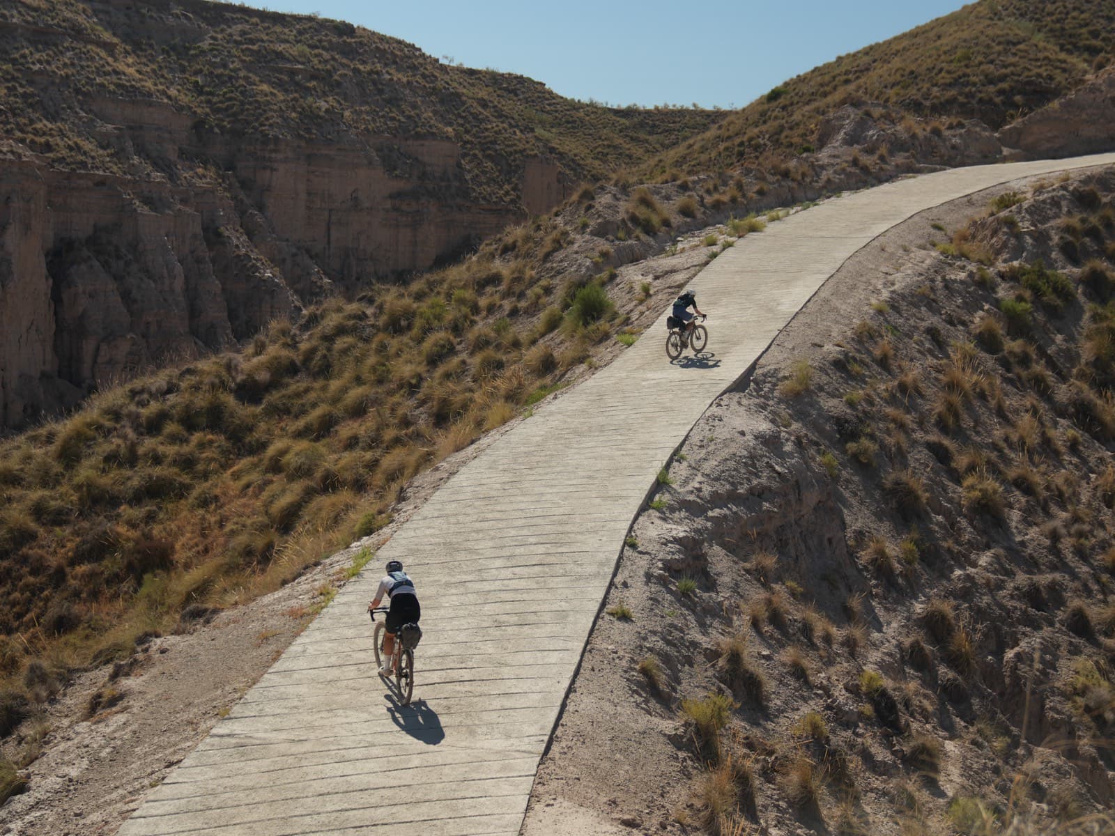Riders on a gravel road through canyon terrain